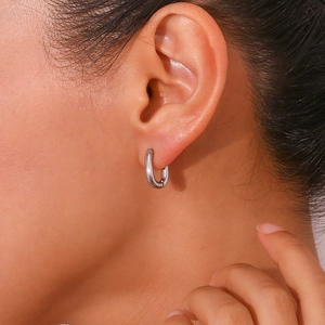 Close-up of minimalist silver U-shaped hoop earring worn on an ear for scale