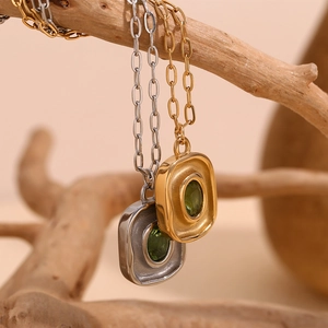 Gros plan du collier en or et argent avec pendentif zircon vert sur des branches