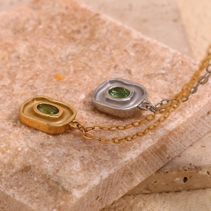 Détail macro de pendentifs or et argent avec zircon vert sur une surface en pierre naturelle