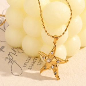 Close-up of gold starfish pendant with sparkling zircons on a round bead chain