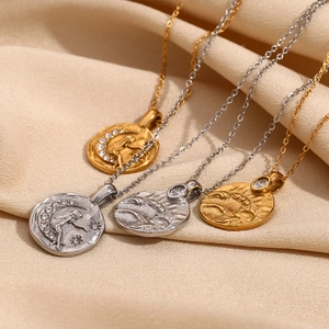 Détail des pendentifs pièces célestes en or 18 carats et argent sur satin plissé