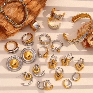 Set di gioielli bicolore con anelli, bracciali e orecchini su uno sfondo di legno naturale