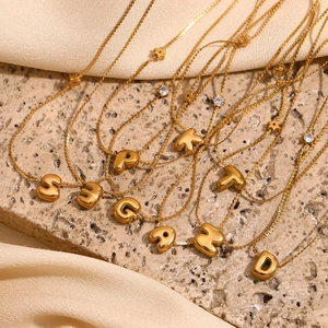 Dettaglio macro di ciondoli a lettere bubble placcati in oro 18K con accenti di zirconi a stella