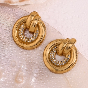 Dettaglio di orecchini ovali placcati oro 18K con finitura martellata e cristalli bianchi