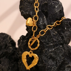 Close-up of 18K gold-plated heart pendant with chunky O-chain and OT buckle on a rock