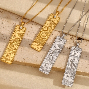 Macro shot of 18K gold and silver zodiac relief pendants with tiny zircon on ball chains