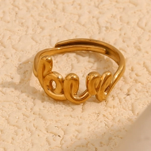 Macro shot of 18K gold plated LOVE script open ring on a textured surface