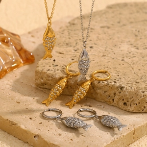 Detailed shot of gold and silver koi fish jewelry set with pave crystals on stone