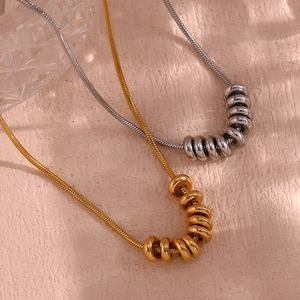 Détail macro de colliers à chaîne serpent dorés et argentés avec pendentifs perles