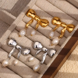 Orecchini a fiocco con doppie perle pendenti in finitura oro e argento su velluto