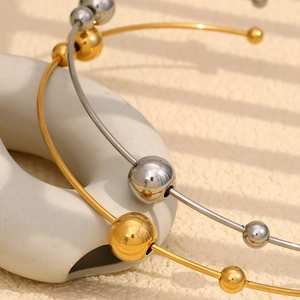Dettaglio di girocolli minimalisti in oro 18 carati e perline d'argento su trama