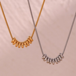 Détail de pendentifs minimalistes plaqués or 18K et argent sur fines chaînes serpent