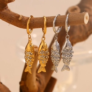 Macro view of gold and silver koi fish hoop earrings with crystal pavé on wood branch