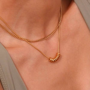 Détail d'un collier double épaisseur doré avec petits anneaux sur chaîne serpent