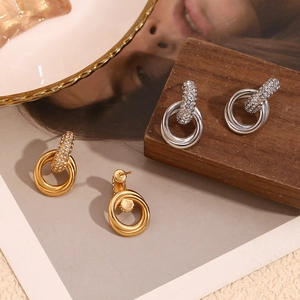 Détail des boucles d'oreilles entrelacées en or 18 carats et argent avec zircons blancs