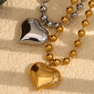 Détail de colliers avec pendentif cœur poli en styles doré et argenté avec chaîne à billes