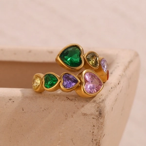 Detail of matte gold heart ring with colorful zircon stones on stone background