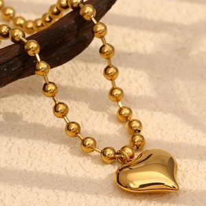 Détail d'un collier en chaîne à billes plaqué or 18 carats avec pendentif cœur poli