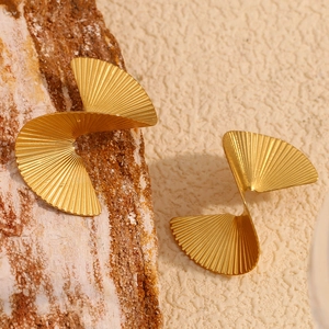 Macro shot of gold-plated twisted fan stud earrings with detailed pleated metal texture
