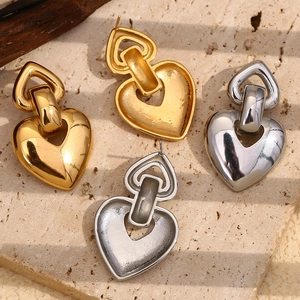 Vue détaillée de boucles d'oreilles en forme de cœur en or et argent sur pierre mate