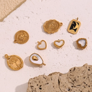 Flachbild von 18K vergoldeten Edelstahl-Anhängern mit Perlmutt und Münzdetails auf Stein