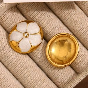 Détail de boucles d'oreilles fleurs en acier inoxydable doré 18K et émail blanc