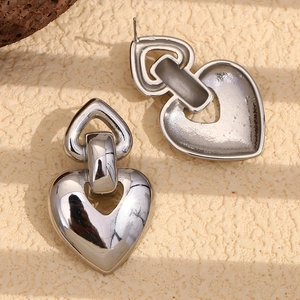 Détail macro de boucles d'oreilles cœur argentées avec finition polie et design miroir