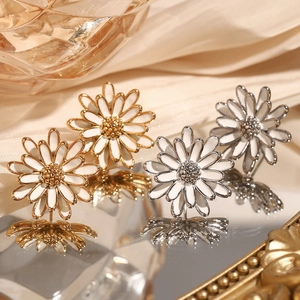 Vue détaillée des boucles d'oreilles marguerites blanches sur un support miroir chic