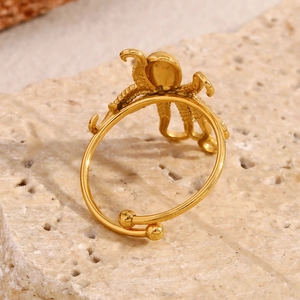Anello polpo placcato oro 18K unico con texture a tentacoli su sfondo di pietra naturale