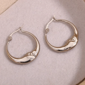 Détail des boucles d'oreilles créoles en argent en forme de visage de lune