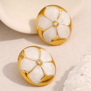 Gros plan de boucles d'oreilles fleur vintage avec émail blanc et placage d'or