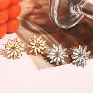 Gros plan détaillé de boucles d'oreilles marguerites en or 18 carats et émail blanc