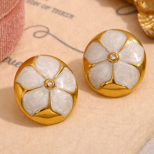 Vue macro de boucles d'oreilles fleur plaquées or 18K avec émail blanc et petit zircon