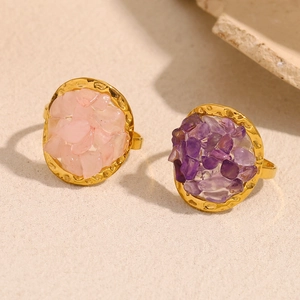 Close-up of 18K gold plated rings with pink and purple crushed stone insets on gravel