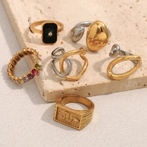 Detail view of mixed-style gold and silver geometric snake rings on stone stand