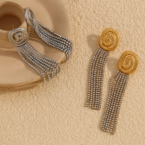 Close-up of dangling fringe earrings with sparkling tassels and hammered metal texture
