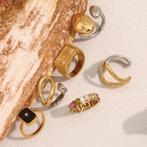 Close-up of geometric two-tone gold rings and colorful zircon jewelry on wood texture