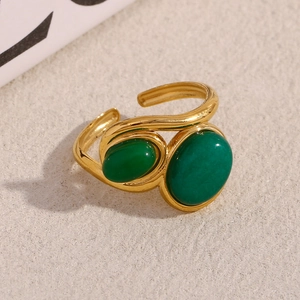 Detail view of gold adjustable ring featuring two oval green emerald-style gemstones