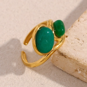 Detailed macro view of an 18K gold-plated open ring with two green emerald-cut stones