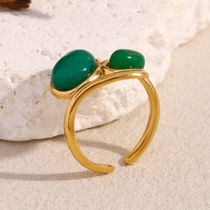 Detail of 18K gold plated stainless steel ring with two green emerald stones on marble