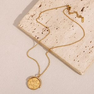 Détail du collier à pendentif lune et étoile doré sur une surface en pierre texturée