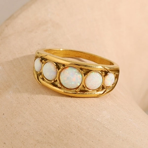 Detail view of gold-plated ring featuring five graduated round white opal stones