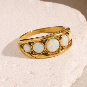 Detailed view of an 18K gold plated ring featuring five white opals on a stone texture