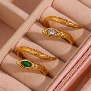 Close-up of gold snake rings with emerald and clear stones in a premium velvet gift box