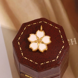 Macro d'un pendentif fleur de cerisier plaqué or 18K et émail blanc sur écrin à bijoux