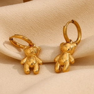 Macro shot of 18K gold plated bear earrings with circular clasp on fabric background