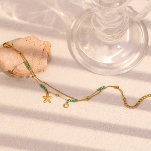 Detailansicht der doppellagigen goldenen Seestern-Fußkette mit grünen Perlen und Zirkon