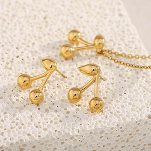 Dettaglio di orecchini a ciliegia e collana in oro 18K su pietra bianca testurizzata