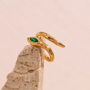 Detail of gold snake ring featuring a vibrant green emerald-cut zircon eye setting