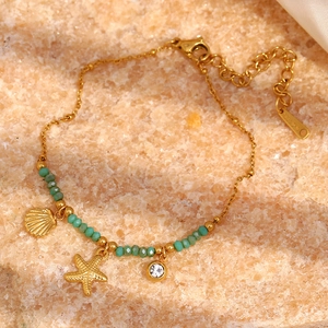 Detail of 18K gold-plated starfish bracelet with green natural stones and charms